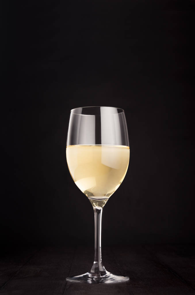 Verre à vin avec vin blanc sur fond élégant en bois noir foncé, espace de copie, vertical
.  - Photo, image