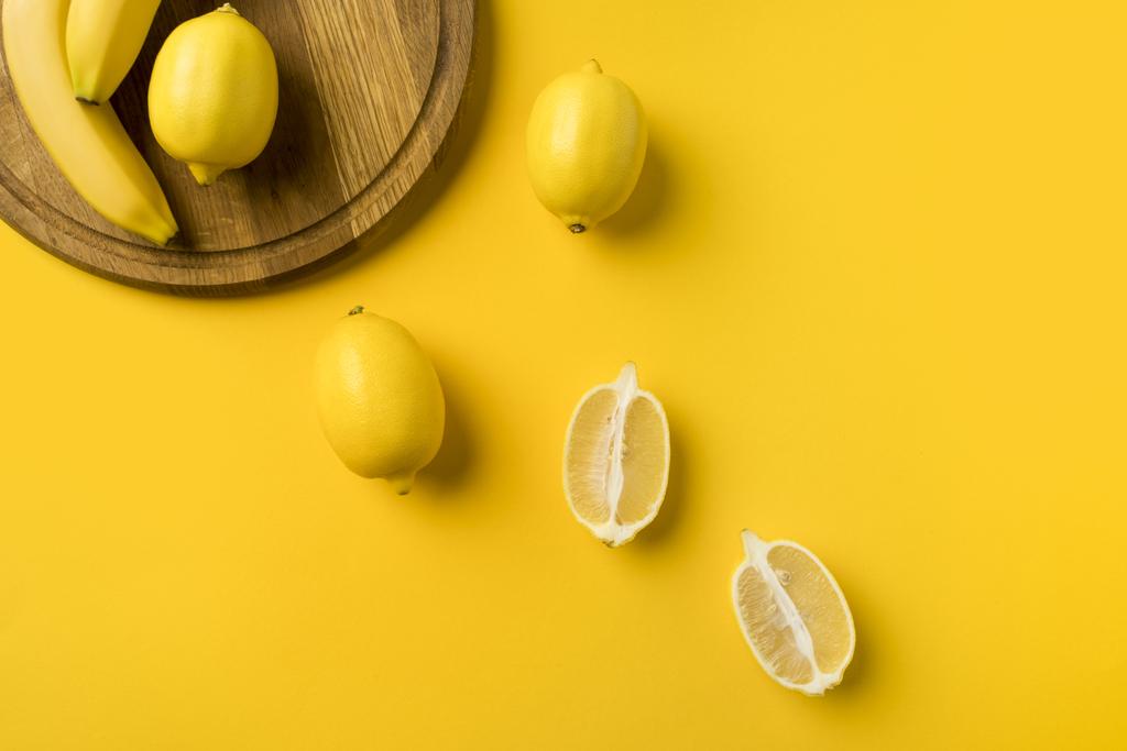 citrony a banány s dřevěnou deskou - Fotografie, Obrázek