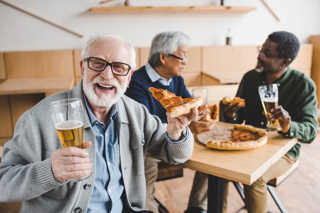 старший чоловік їсть піцу з пивом
 - Фото, зображення