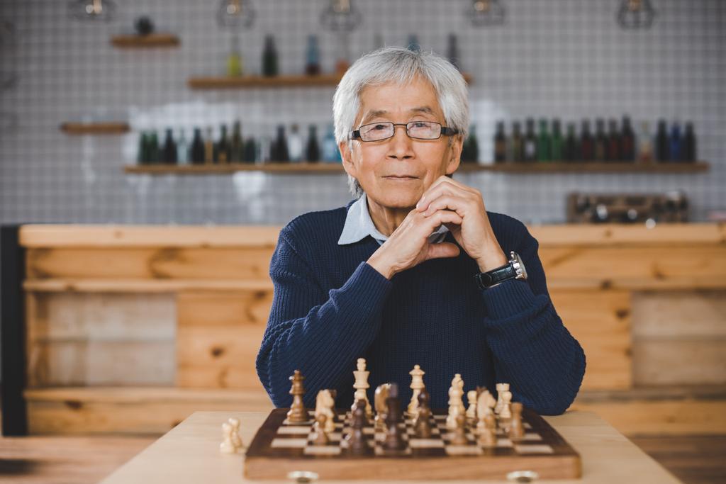 hombre asiático con tablero de ajedrez
 - Foto, imagen