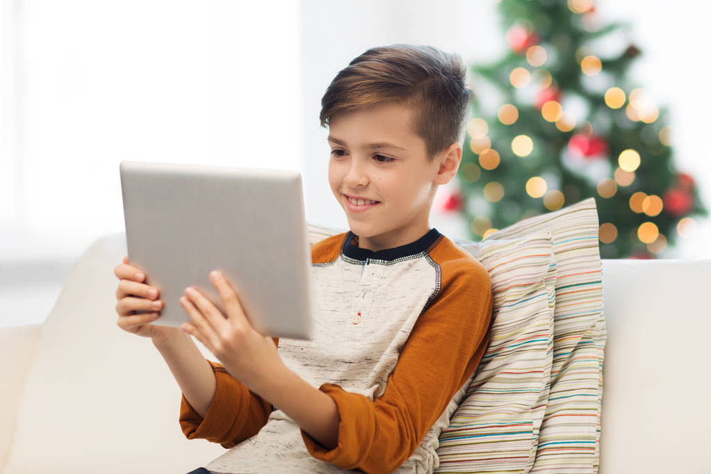 niño sonriente con la tableta PC en casa en Navidad
 - Foto, imagen