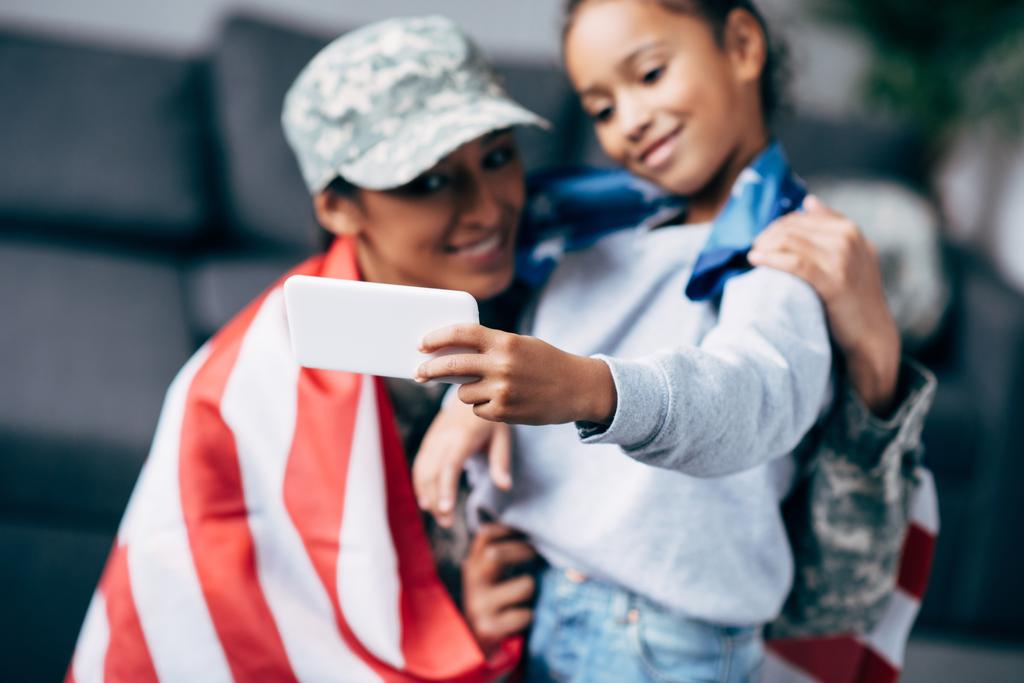 Córka i żołnierz z flaga biorąc selfie - Zdjęcie, obraz