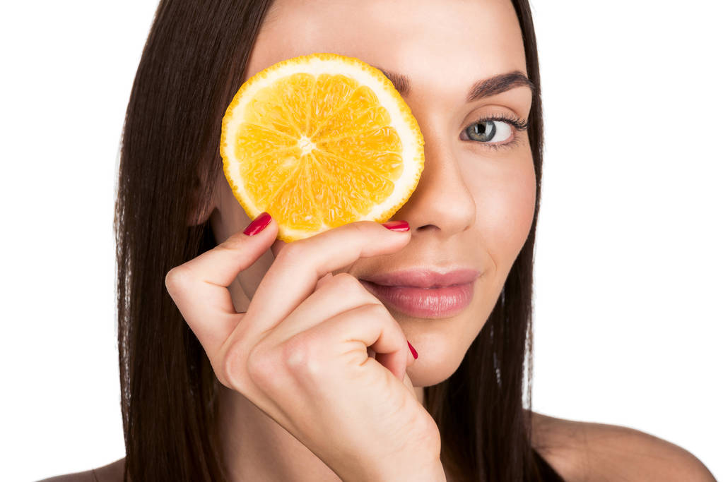 mulher cobrindo olho com fatia de laranja
 - Foto, Imagem