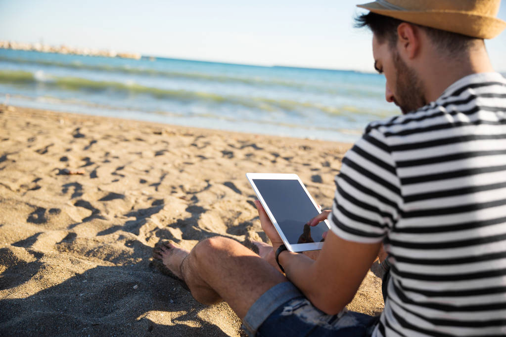 電子ブックを読むのビーチに座っている男 - 写真・画像