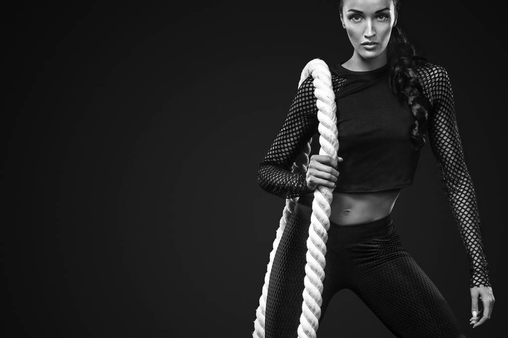 Sporty bella donna con corda da battaglia fa fitness esercizio su sfondo nero per rimanere in forma
 - Foto, immagini