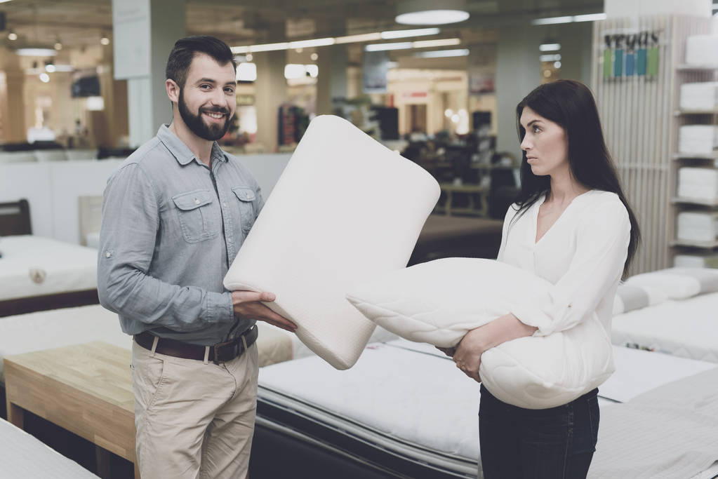 A couple in a large store of beds and mattresses chooses pillows. They examine several variants of pillows - Photo, Image