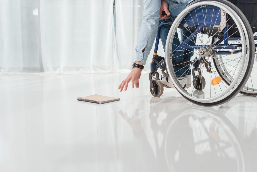 мужчина на инвалидной коляске пытается дотянуться до книги
 - Фото, изображение