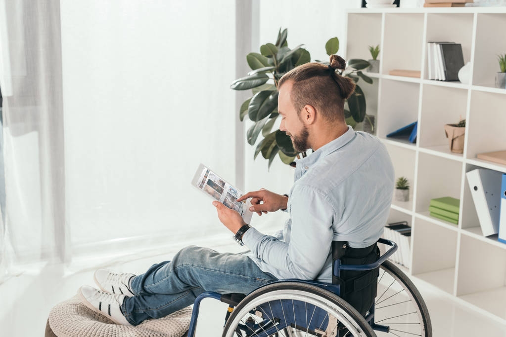 homem em cadeira de rodas usando comprimido
 - Foto, Imagem