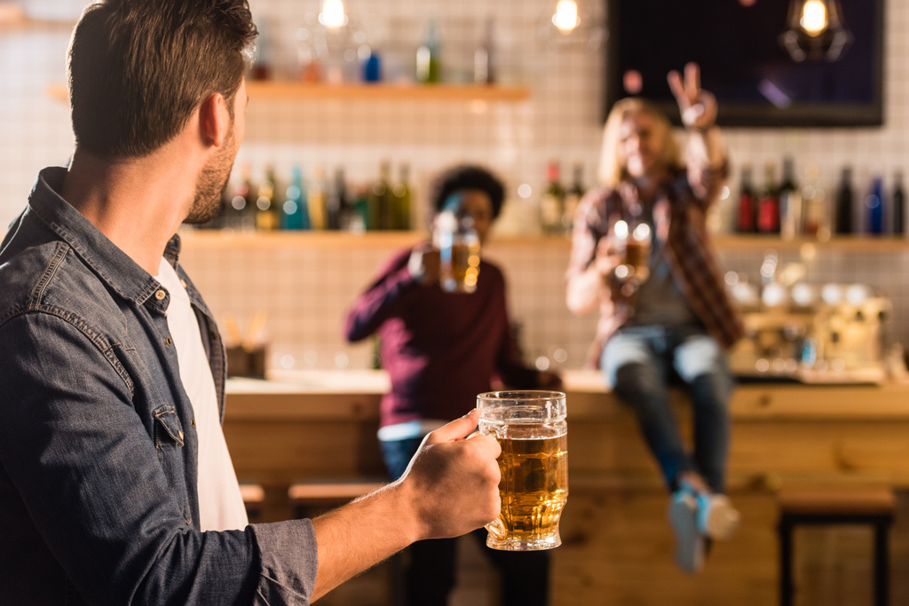 мужчина с пивом смотрит на друзей
 - Фото, изображение