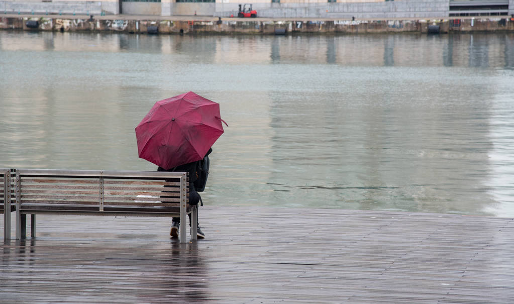 Εφηβικό κορίτσι ssitting σε ένα ξύλινο παγκάκι στη βροχή - Φωτογραφία, εικόνα