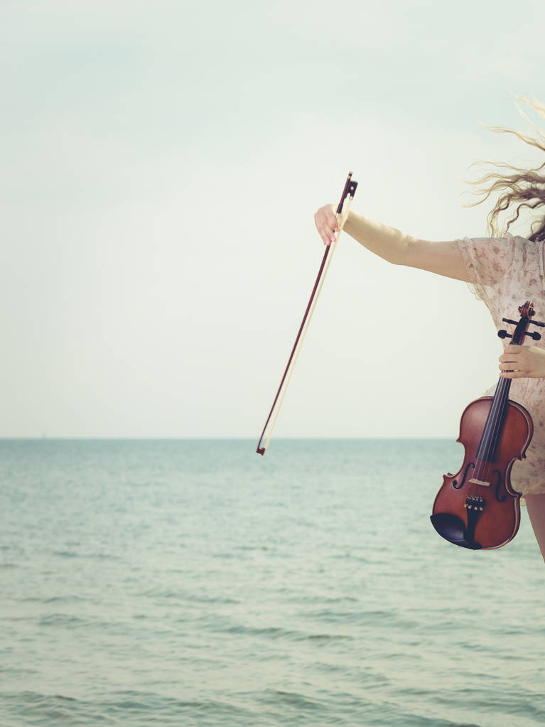Femme sur la plage près de la mer tenant violon
 - Photo, image