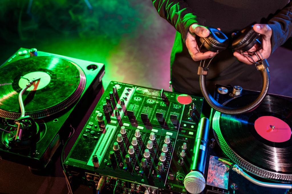 DJ з навушниками над звуковим мікшером
 - Фото, зображення