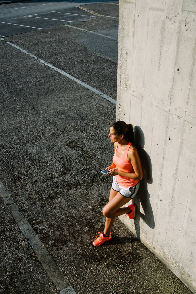 Mulher desportiva usando smartphone para mensagens de texto durante o treino urbano r
 - Foto, Imagem
