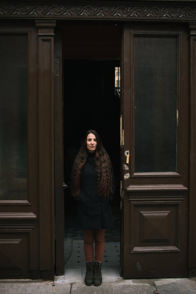 Стильная девушка в черном пальто, стоящая во дворе. Фото в черно-белом стиле
. - Фото, изображение