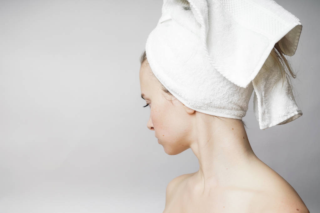 Mooie vrouw met een handdoek over het hoofd op zoek naar camera, glimlach - Foto, afbeelding