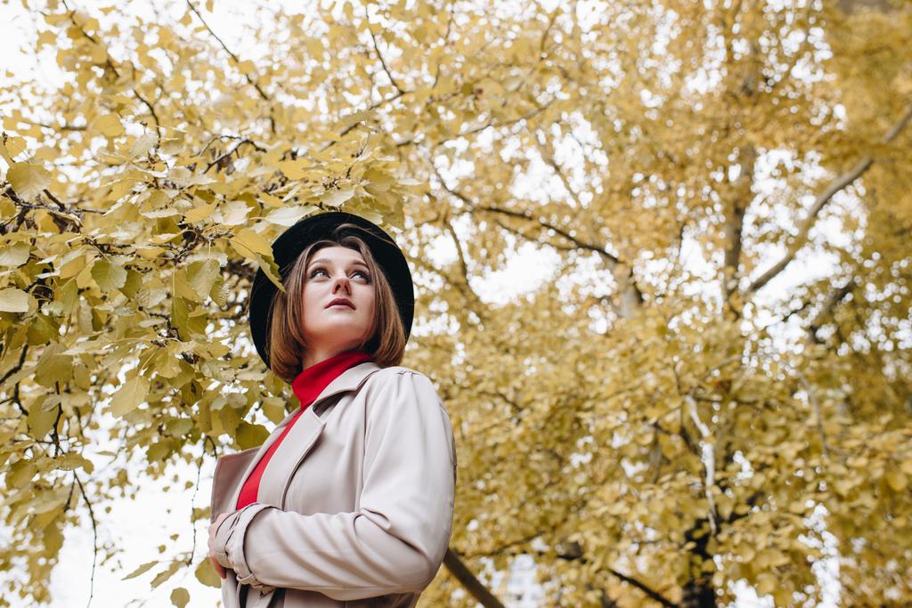 mulher em casaco de trincheira e chapéu no parque
 - Foto, Imagem