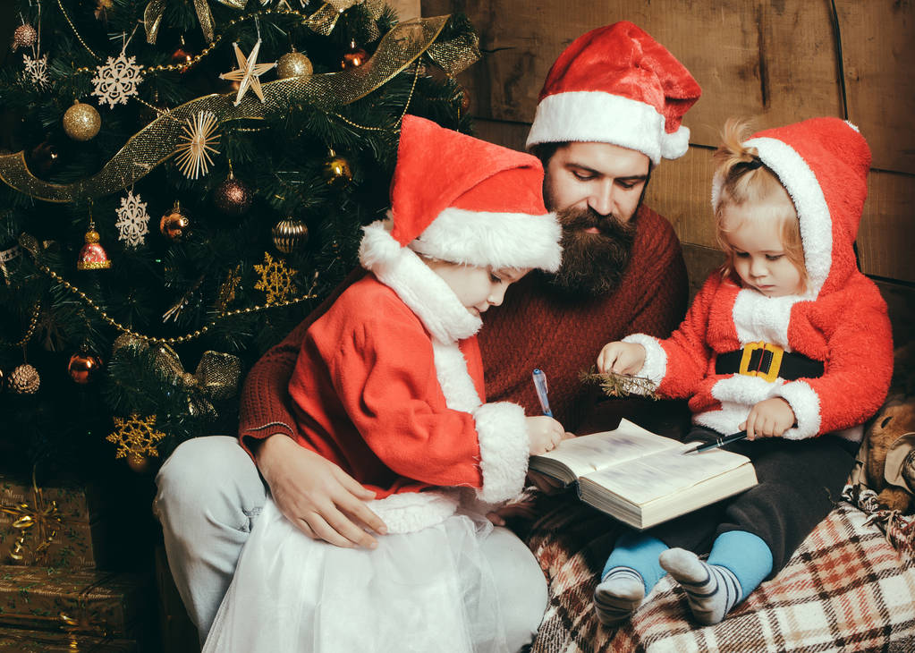 Weihnachtsfamilie mit bärtigem Vater und Kindern im Weihnachtsmann-Hut - Foto, Bild
