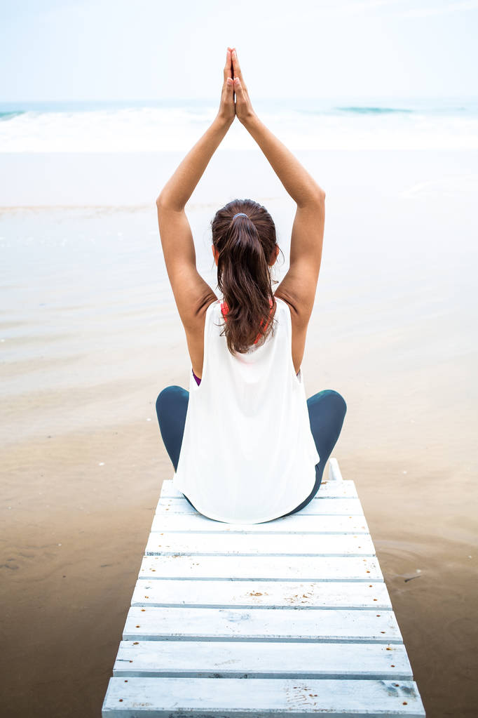 Жінка практикує йогу на березі моря в похмурий день
 - Фото, зображення