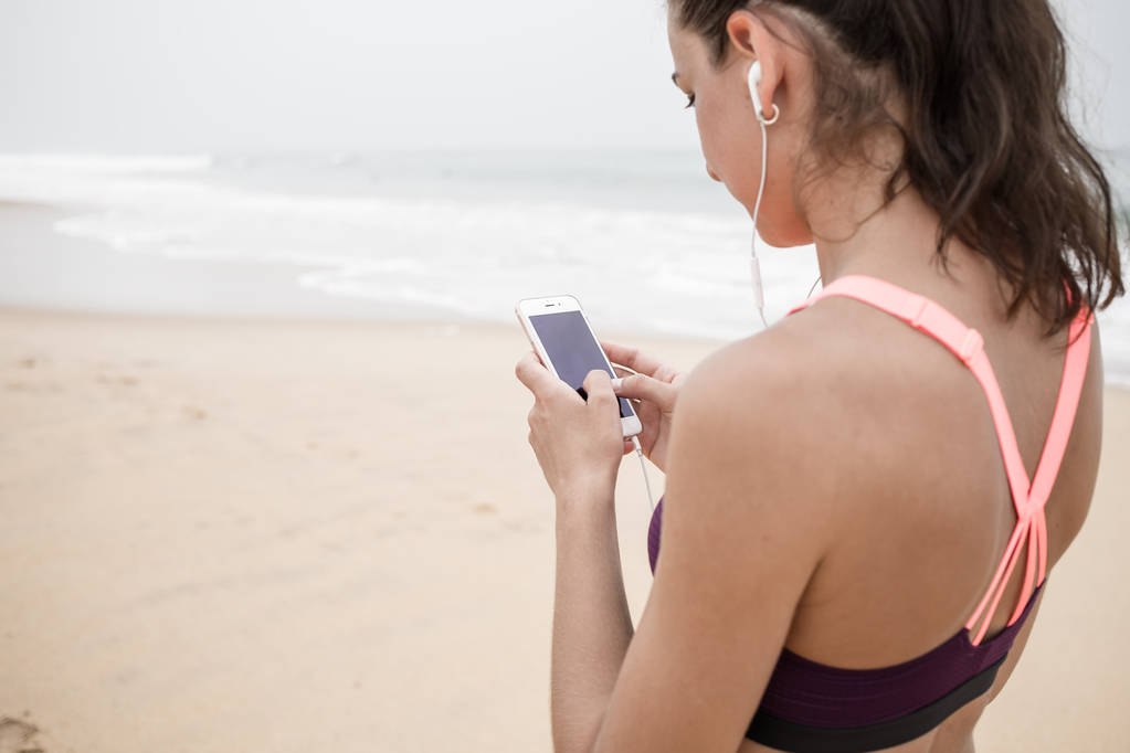 Mujer joven y activa escuchando música en auriculares
 - Foto, Imagen