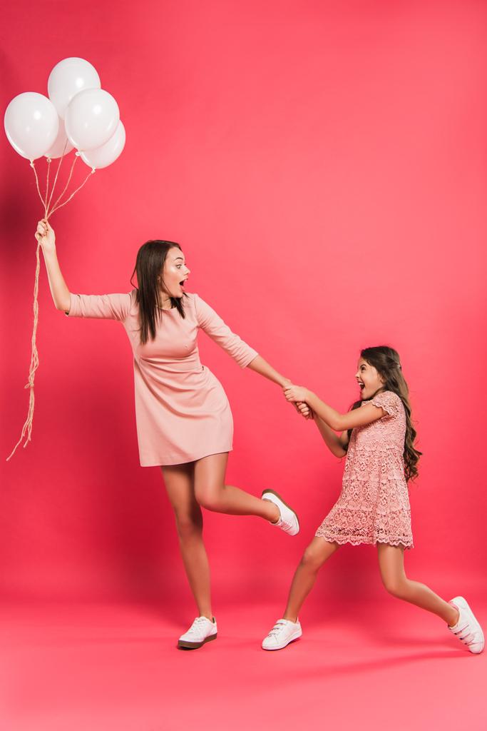 Daughter holding mother with helium balloons - Photo, Image