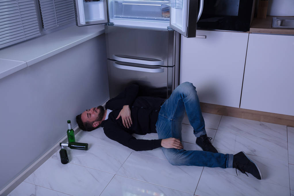 Hombre acostado en el piso en la cocina
 - Foto, Imagen