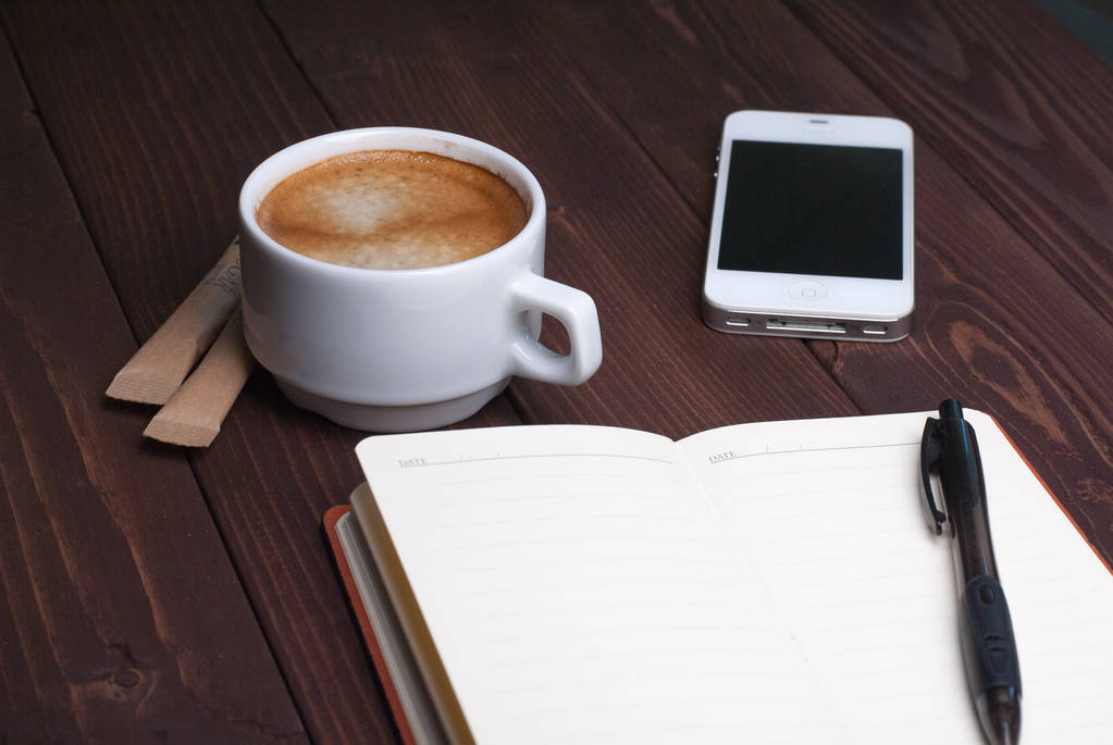 Smartphone-val jegyzetfüzet és erős kávét, fából készült háttér - Fotó, kép