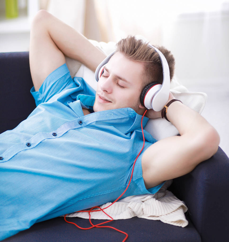 Hombre escuchando música con auriculares en casa
 - Foto, imagen