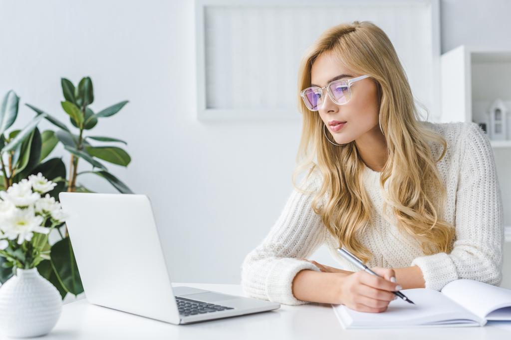 blonde zakenvrouw schrijven en workig met laptop - Foto, afbeelding