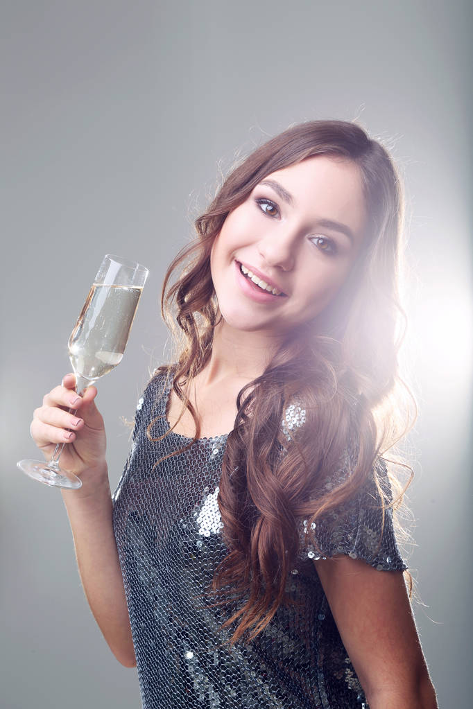 灰色の背景の上のシャンパンのグラスを持つ若い女性 - 写真・画像