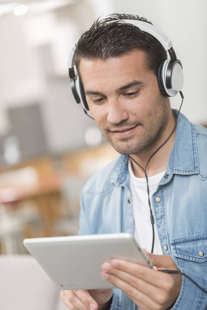 csinos, fiatal férfi listenning zene wwith a tabletta portréja egy - Fotó, kép