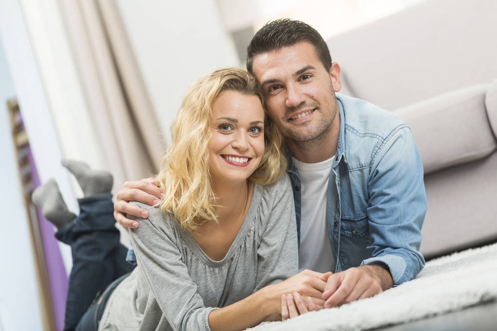 Felice giovane coppia posato sul tappeto del loro soggiorno
 - Foto, immagini
