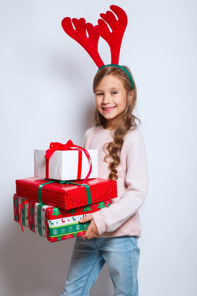 joyeux Noël et bonne année .happy petite fille souriante avec des boîtes-cadeaux de Noël.. Enfant drôle souriant dans des cornes de cerf
 - Photo, image