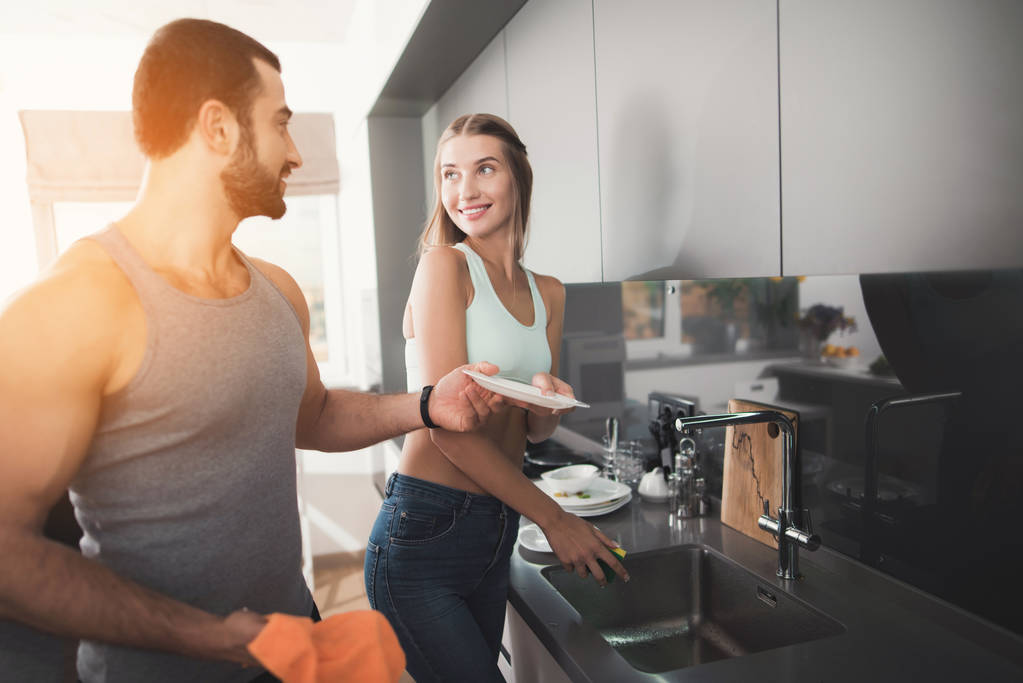 Чоловік і жінка на кухні вранці. Після сніданку миють посуд.
. - Фото, зображення