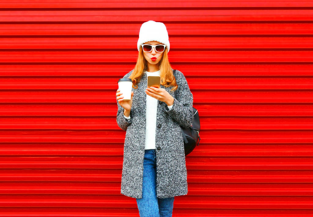 Módní hezká mladá žena s pomocí smartphone na šálek kávy - Fotografie, Obrázek