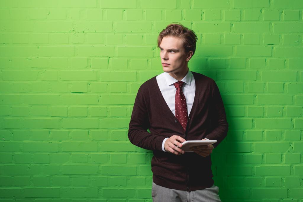 młody biznesmen z cyfrowego tabletu przed zielony ściana - Zdjęcie, obraz