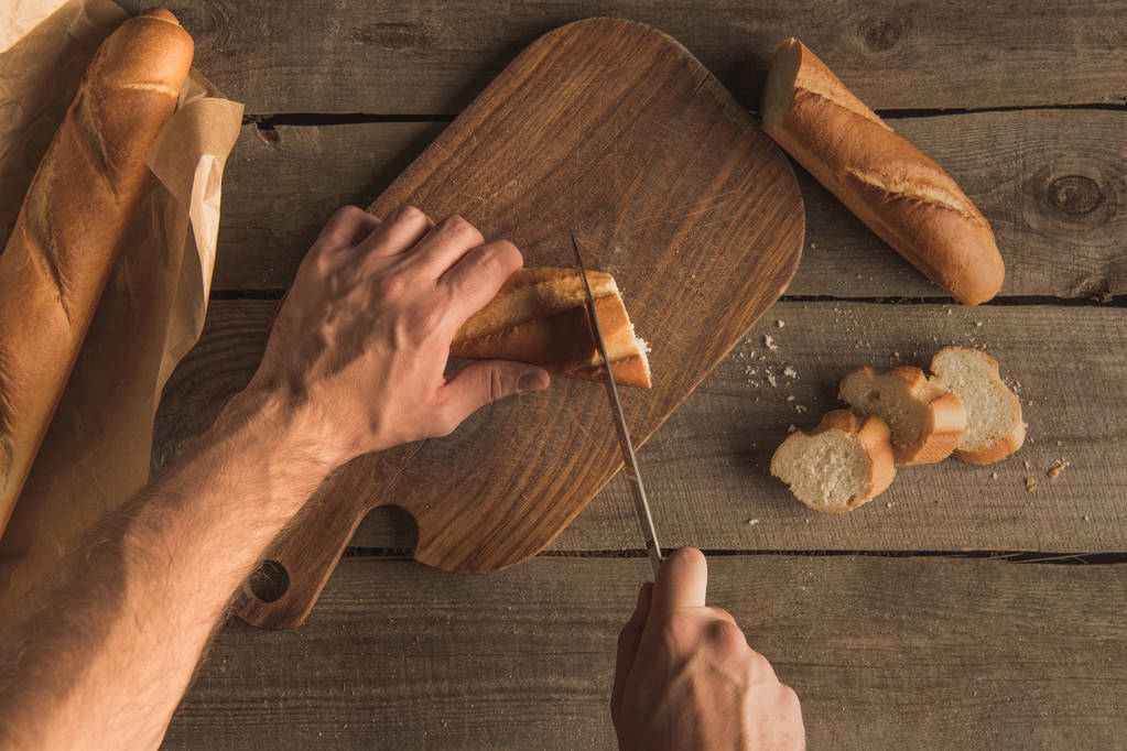 person slicing baguette - Photo, Image