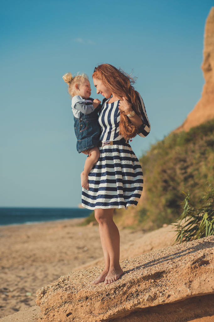 schöne Mutter Dame mit niedlichen Tochter Mädchen auf einem Strand am Meer stilvoll gekleidet. - Foto, Bild