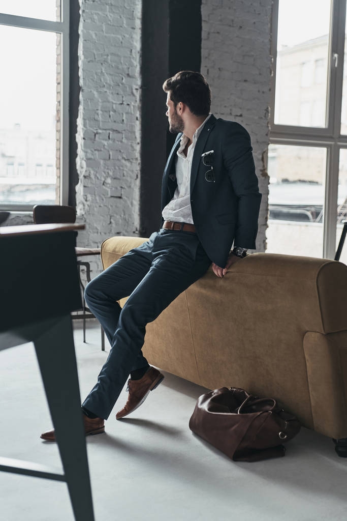 бизнесмен в костюме опирается на диван
 - Фото, изображение
