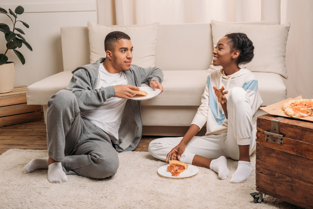 ソファの横にピザを食べるカップル - 写真・画像