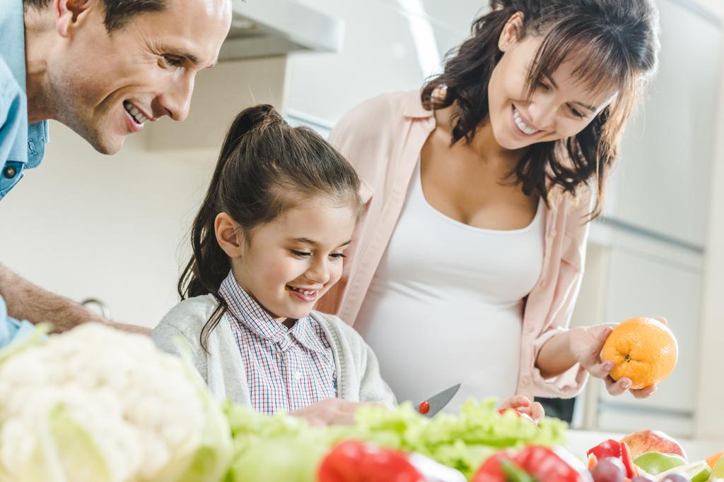 счастливая улыбающаяся семья делает салат вместе на кухне
  - Фото, изображение