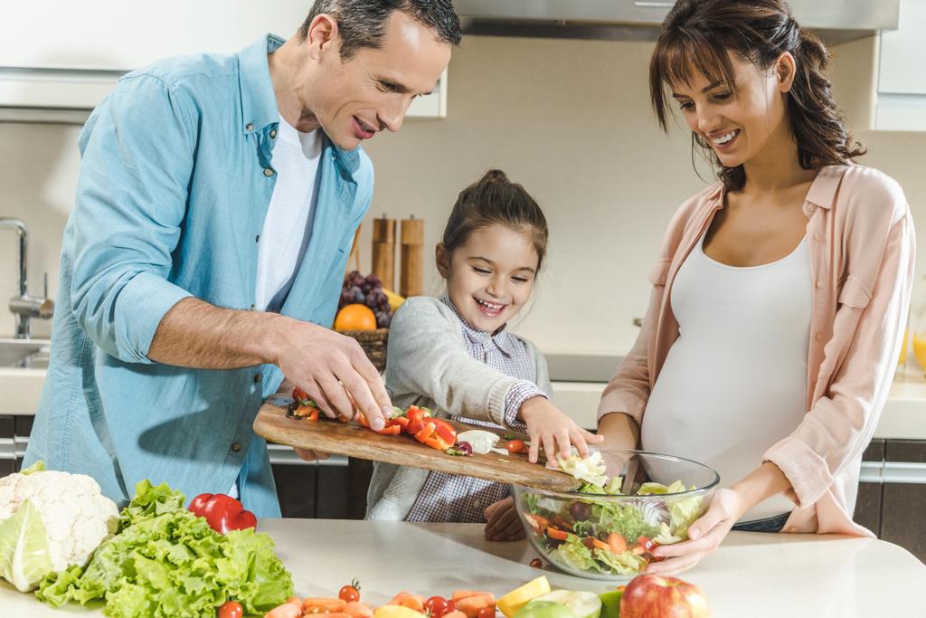 usmívající se rodina dělat salát spolu v kuchyni  - Fotografie, Obrázek