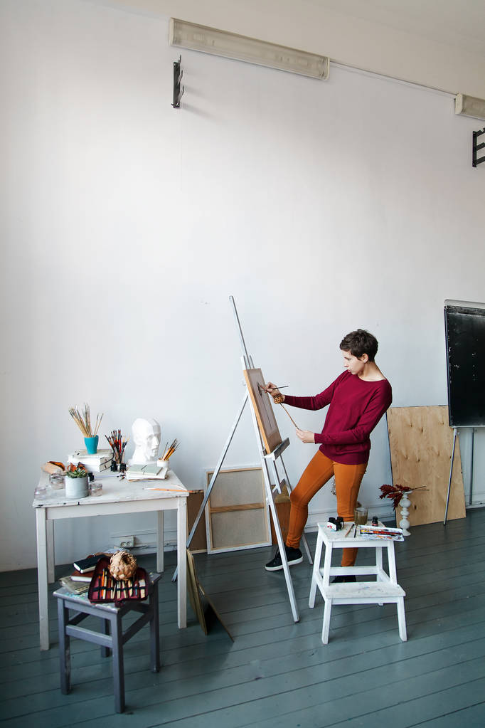 Artista femenina en su espacioso estudio blanco que trabaja con la pintura de acuarela. La iluminación natural. Divulgación del concepto de creatividad. Composición vertical con espacio de copia
 - Foto, Imagen