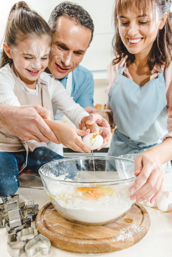 rajattu kuva onnellinen perhe halkaisu muna kulhoon keittiössä
 - Valokuva, kuva
