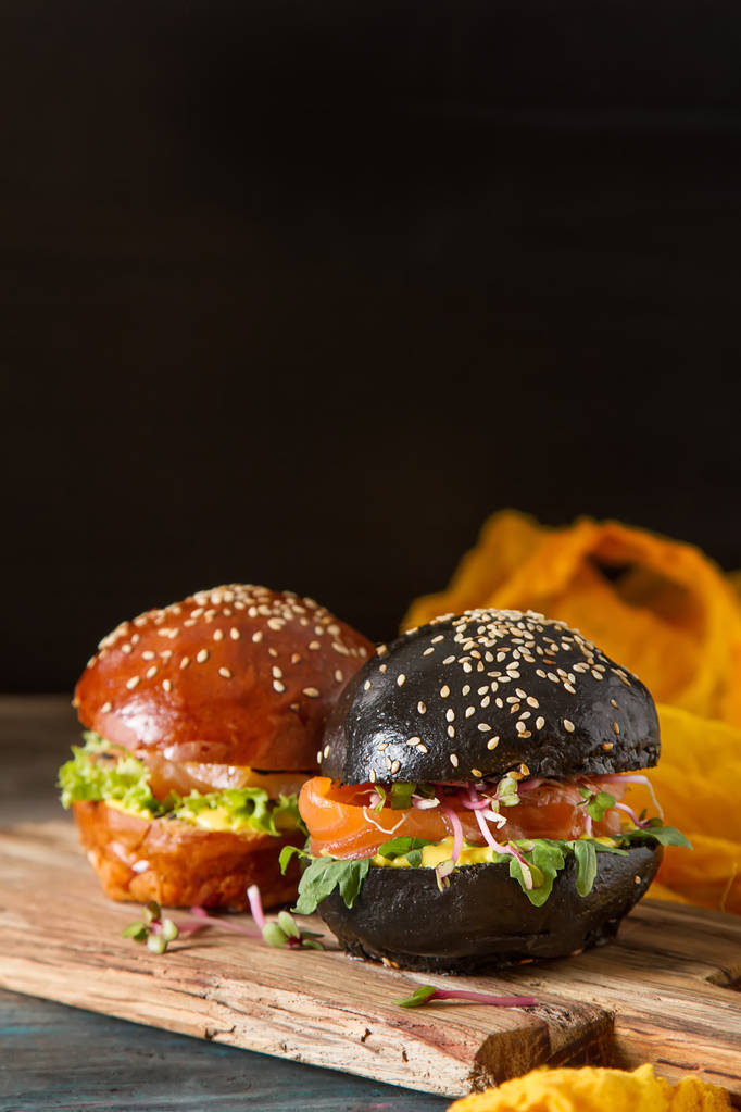 Černý burger s lososem, hlávkový salát, hořčice. Tmavé pozadí - Fotografie, Obrázek
