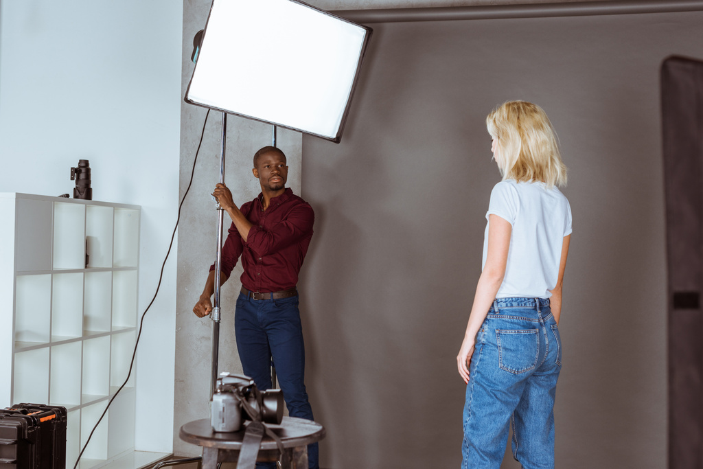 african american photographer correcting light before photoshoot in studio - Photo, Image