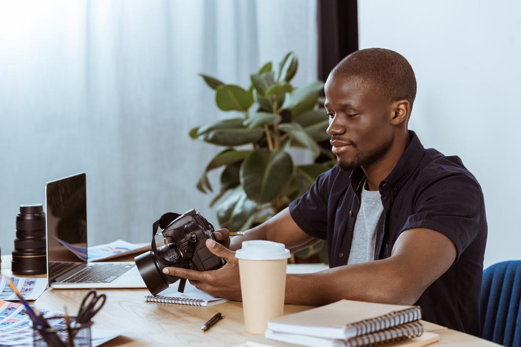 職場のオフィスでノート パソコンで写真のカメラとアフリカ系アメリカ人の写真家の肖像画  - 写真・画像