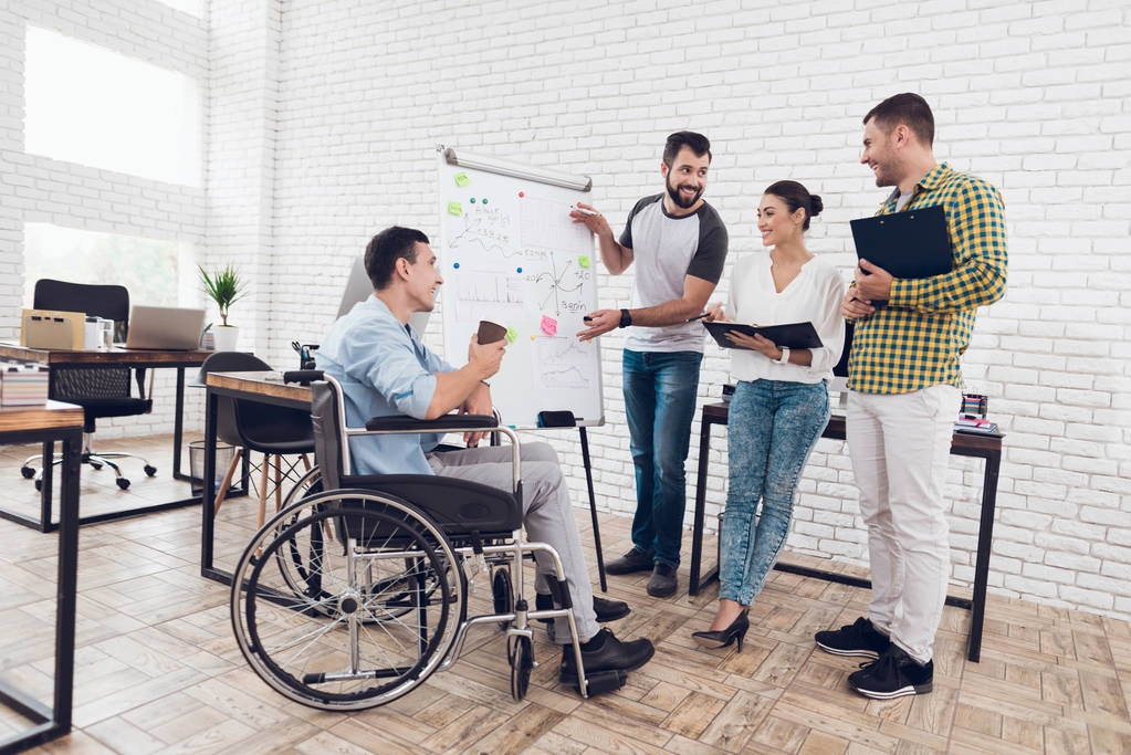 Administrativní pracovníci a muž na invalidním vozíku, diskuse o obchodní okamžiky při práci v moderní kanceláři. - Fotografie, Obrázek