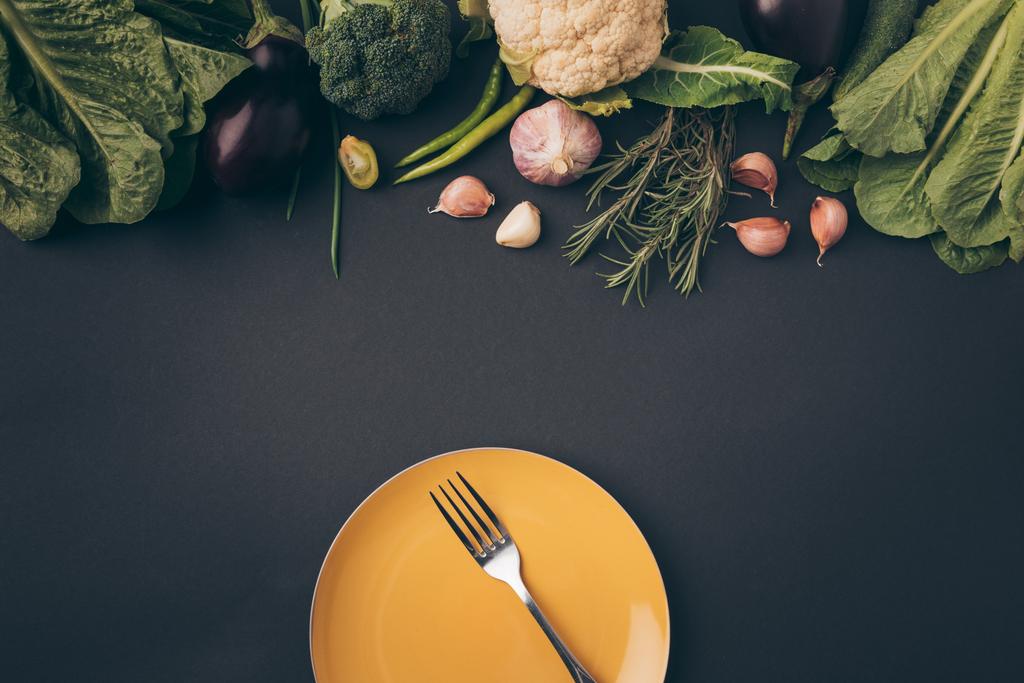 το Top view πιρουνιού σε πιάτο και λαχανικά σε γκρίζο πίνακα - Φωτογραφία, εικόνα
