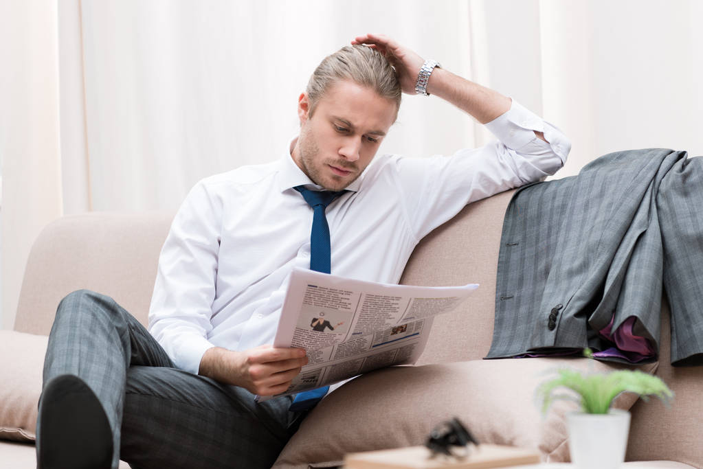 koncentrált üzletember olvasó újság otthon a kanapén - Fotó, kép
