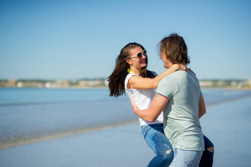 Na pobřeží chlap drží dívku na rukou. - Fotografie, Obrázek